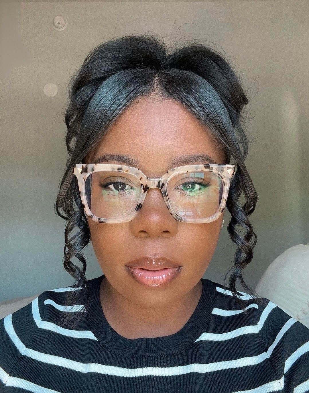 Derrian West wearing glasses and a striped sweater